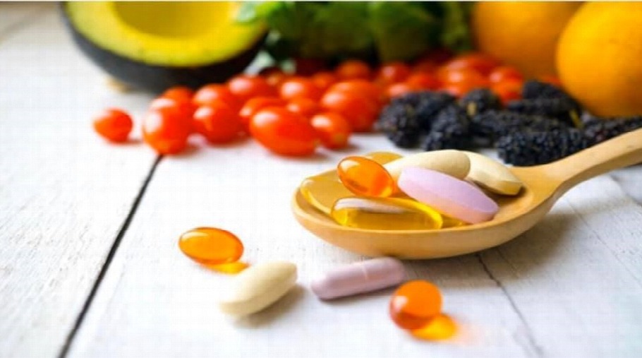Fruits and vitamin capsules spread across a table